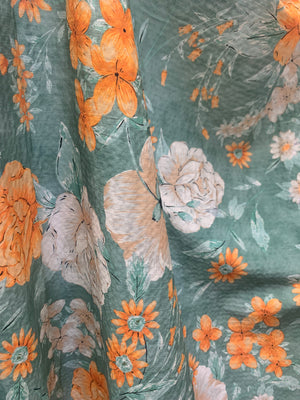 flat cotton seersucker with a muted green, orange and white floral print