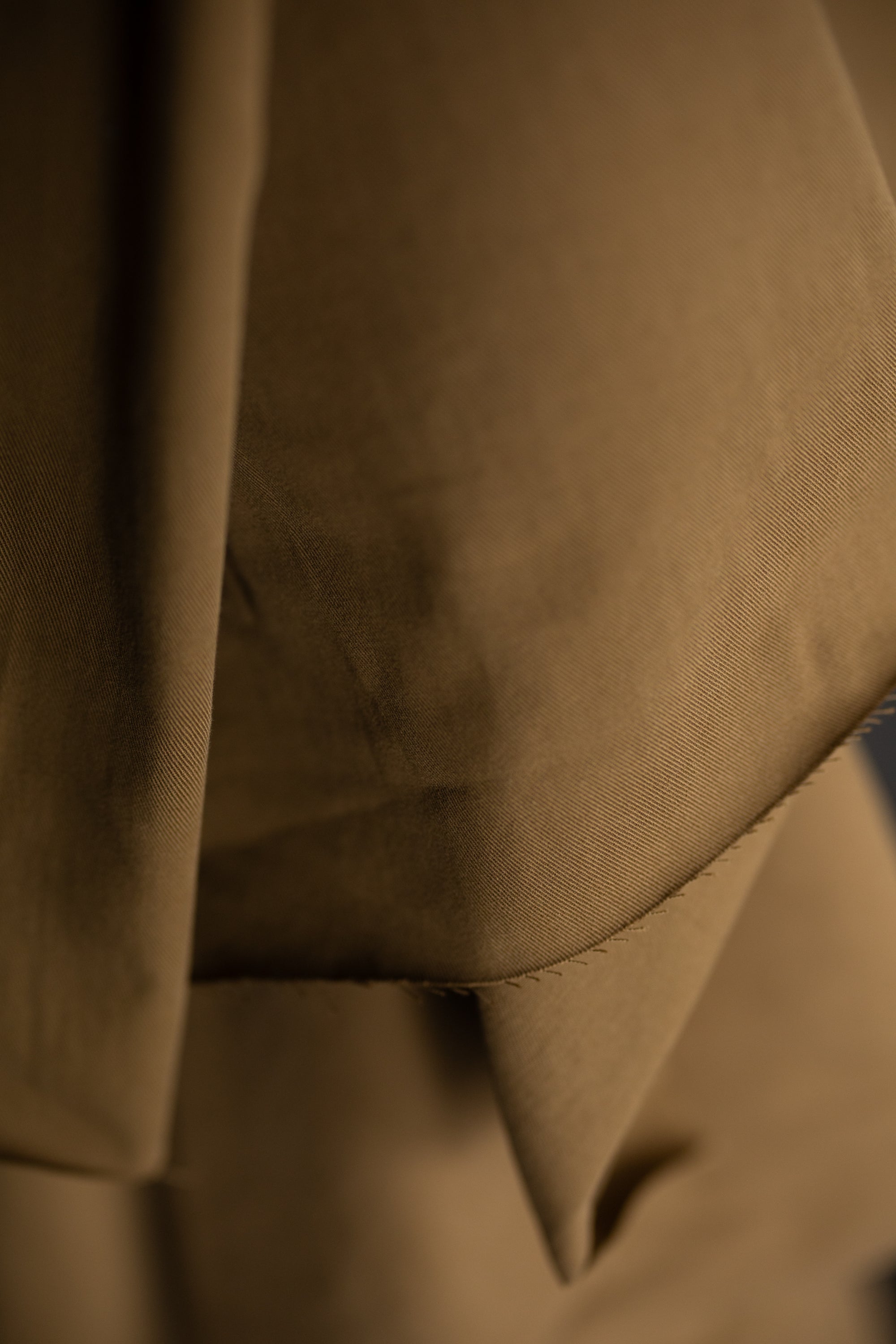 roll of Olive Tan sanded cotton twill fabric on a dark grey background.