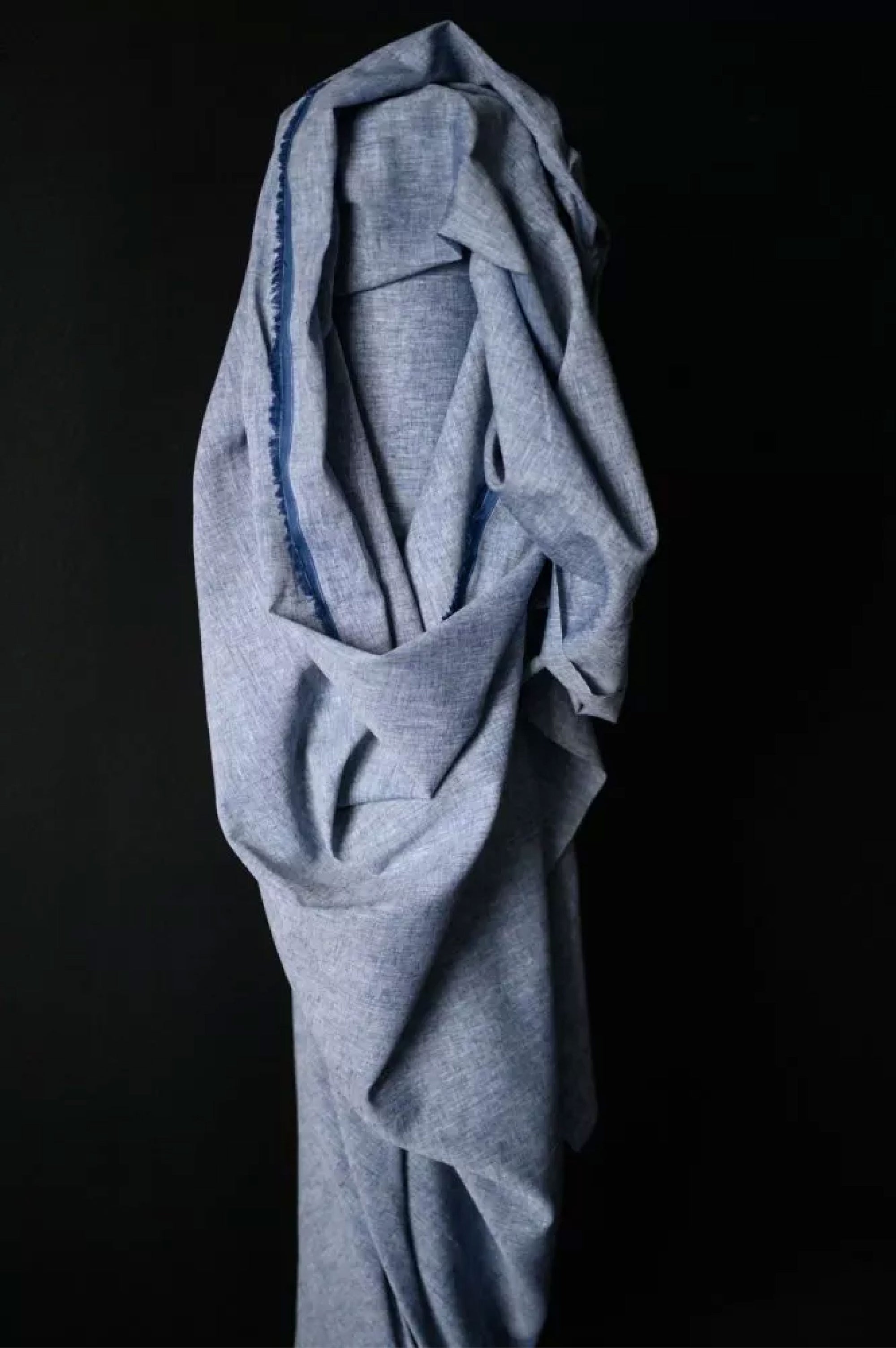 A roll of classic denim bright blue chambray on a dark navy background.