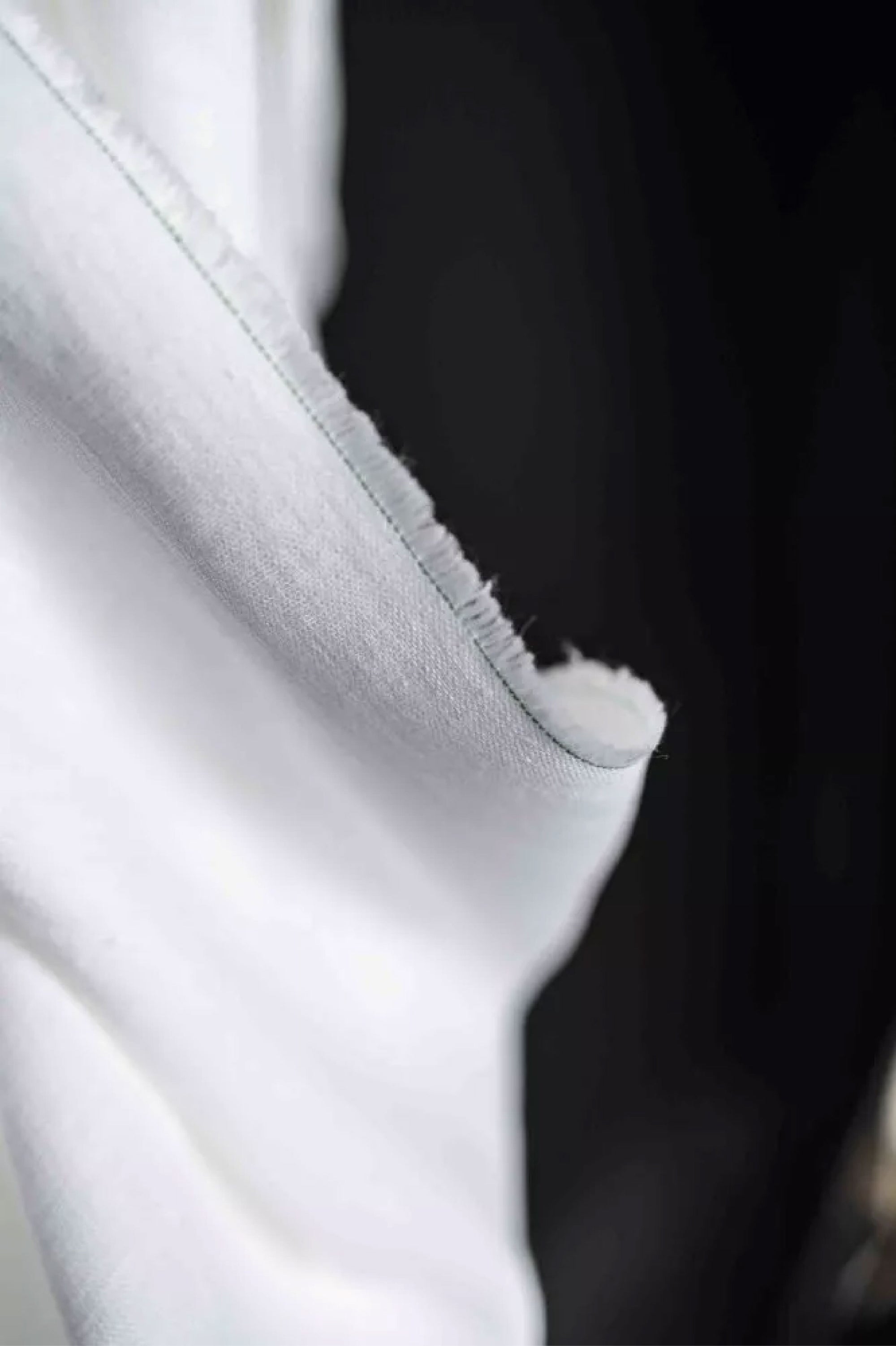 close up of European laundered linen in pure white on a dark grey background.