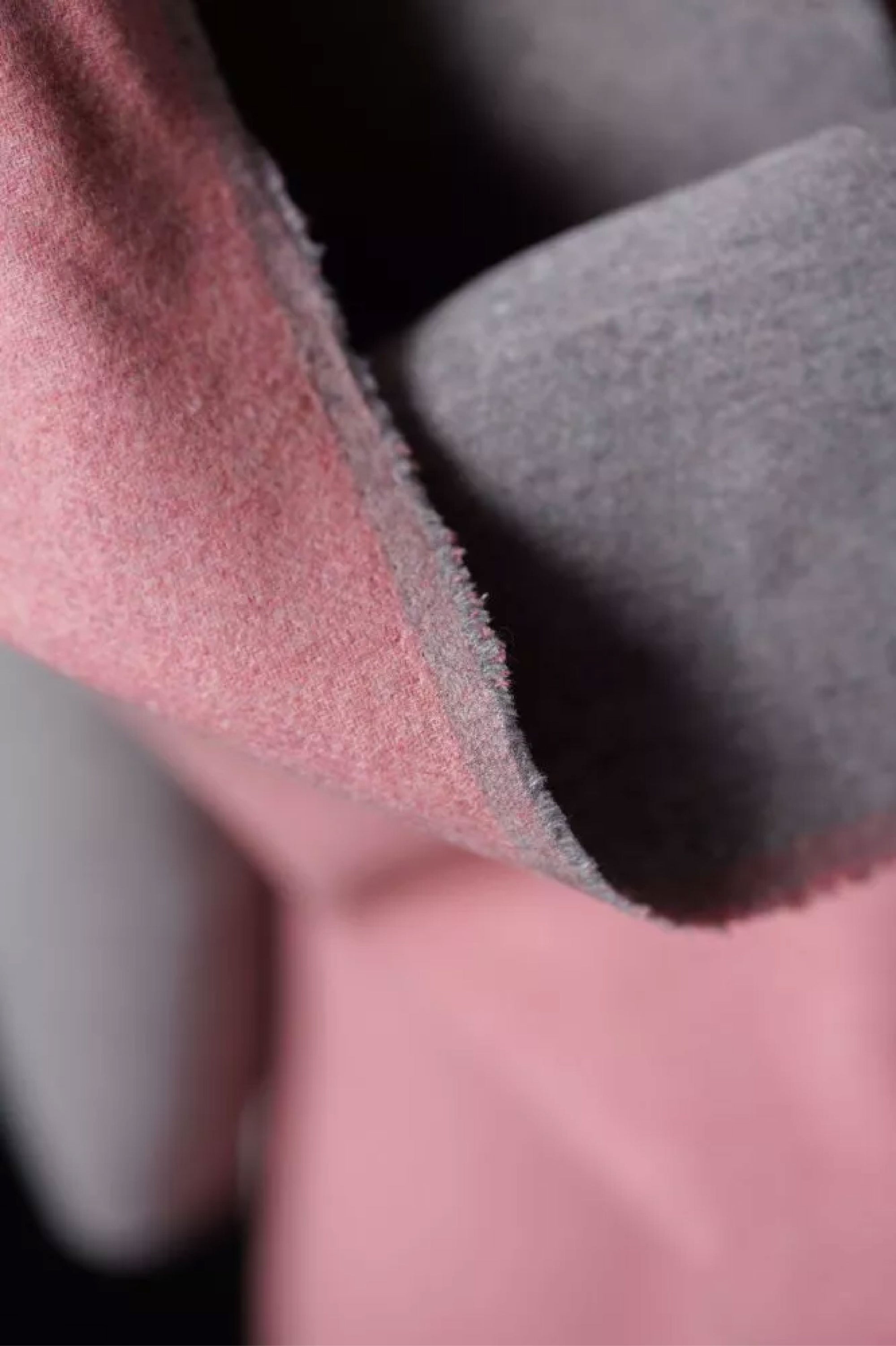 A close up of A soft and bouncy two toned wool in bright bubblegum pink on one side and grey marl on the other.