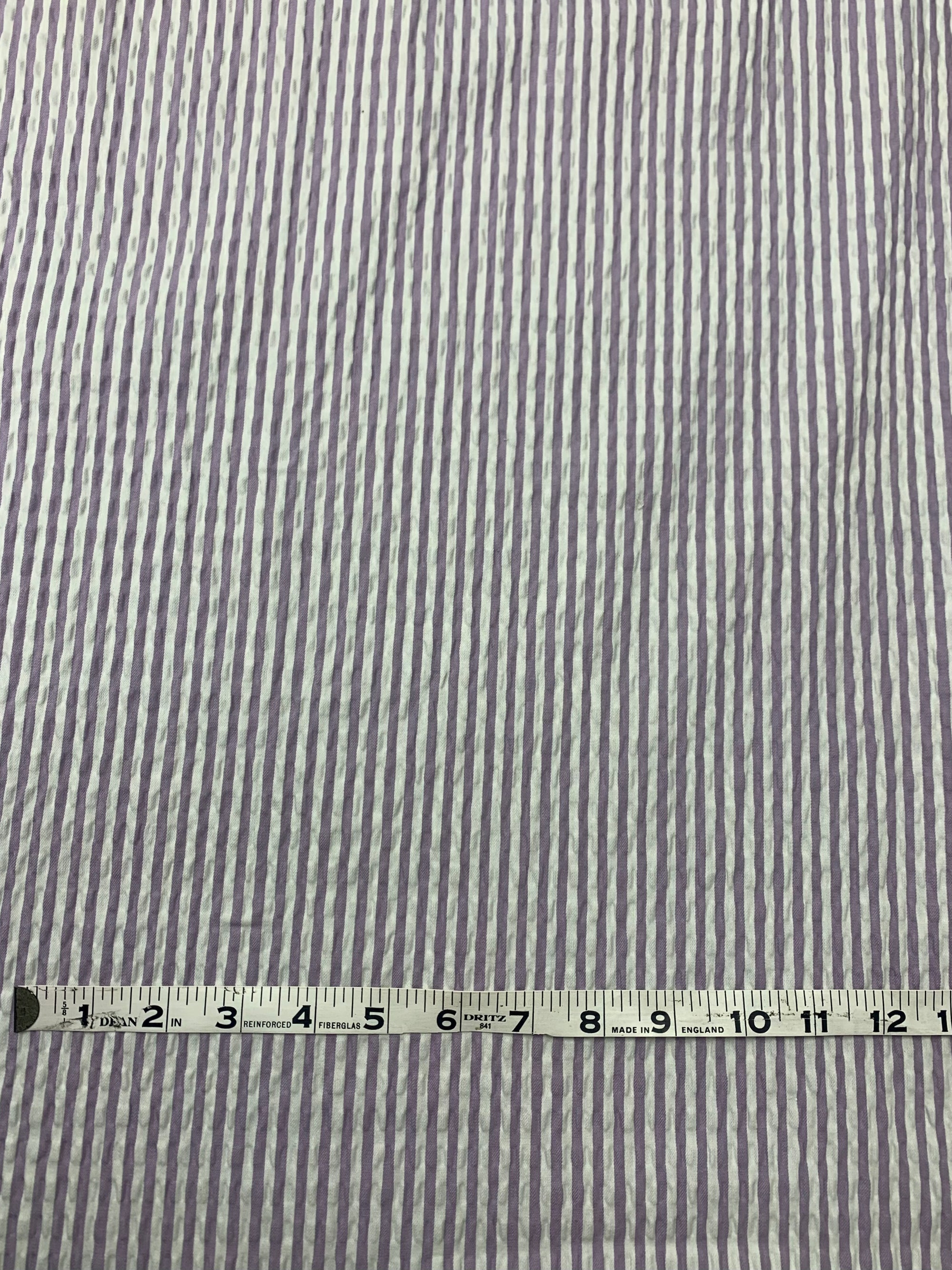 A spiraled  cotton seersucker fabric in a striped Lilac and White vertically