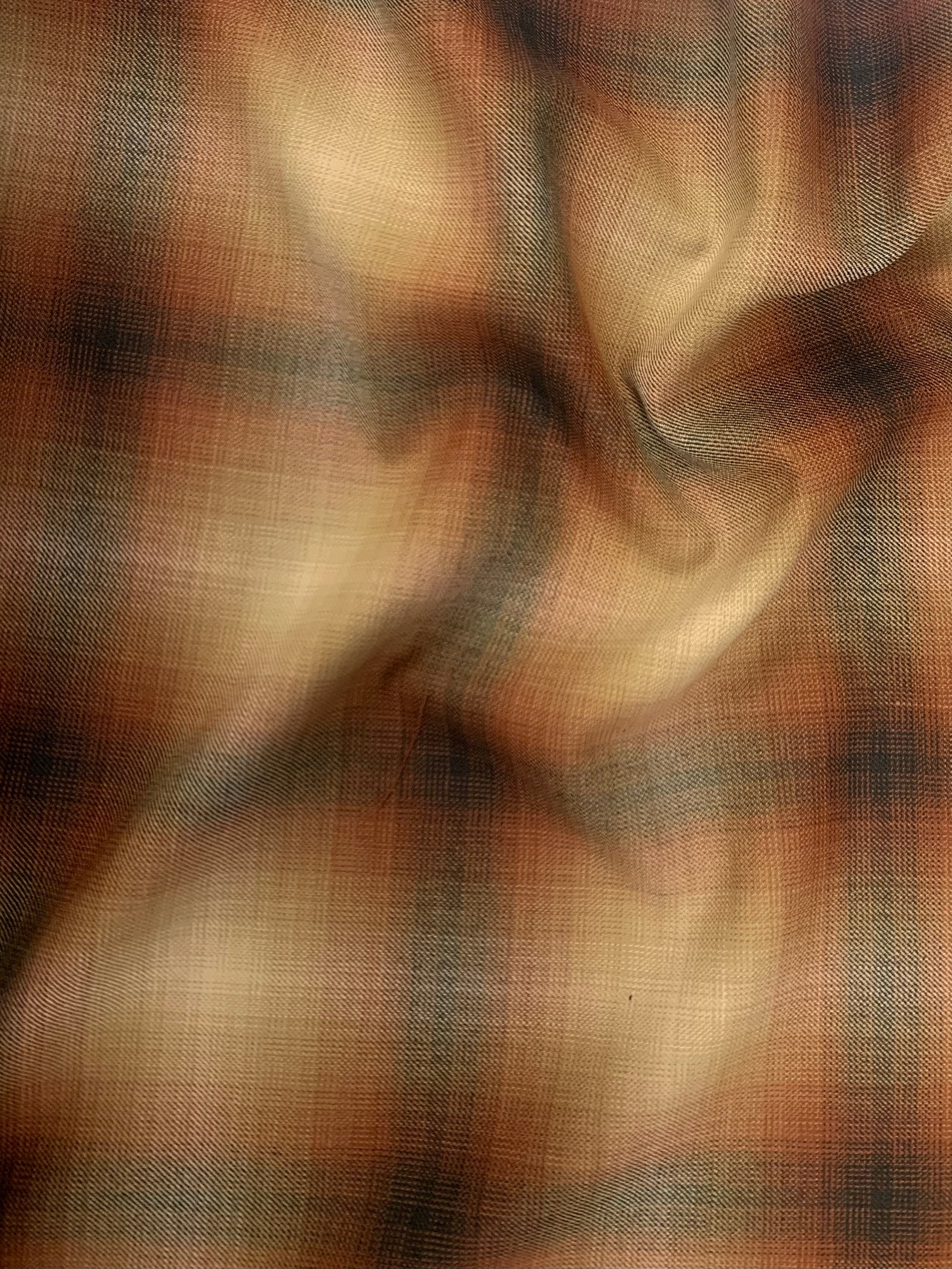 A beautiful soft light to medium-weight yarn dyed wool in a pretty plaid (light brown, black, and deep orange). 