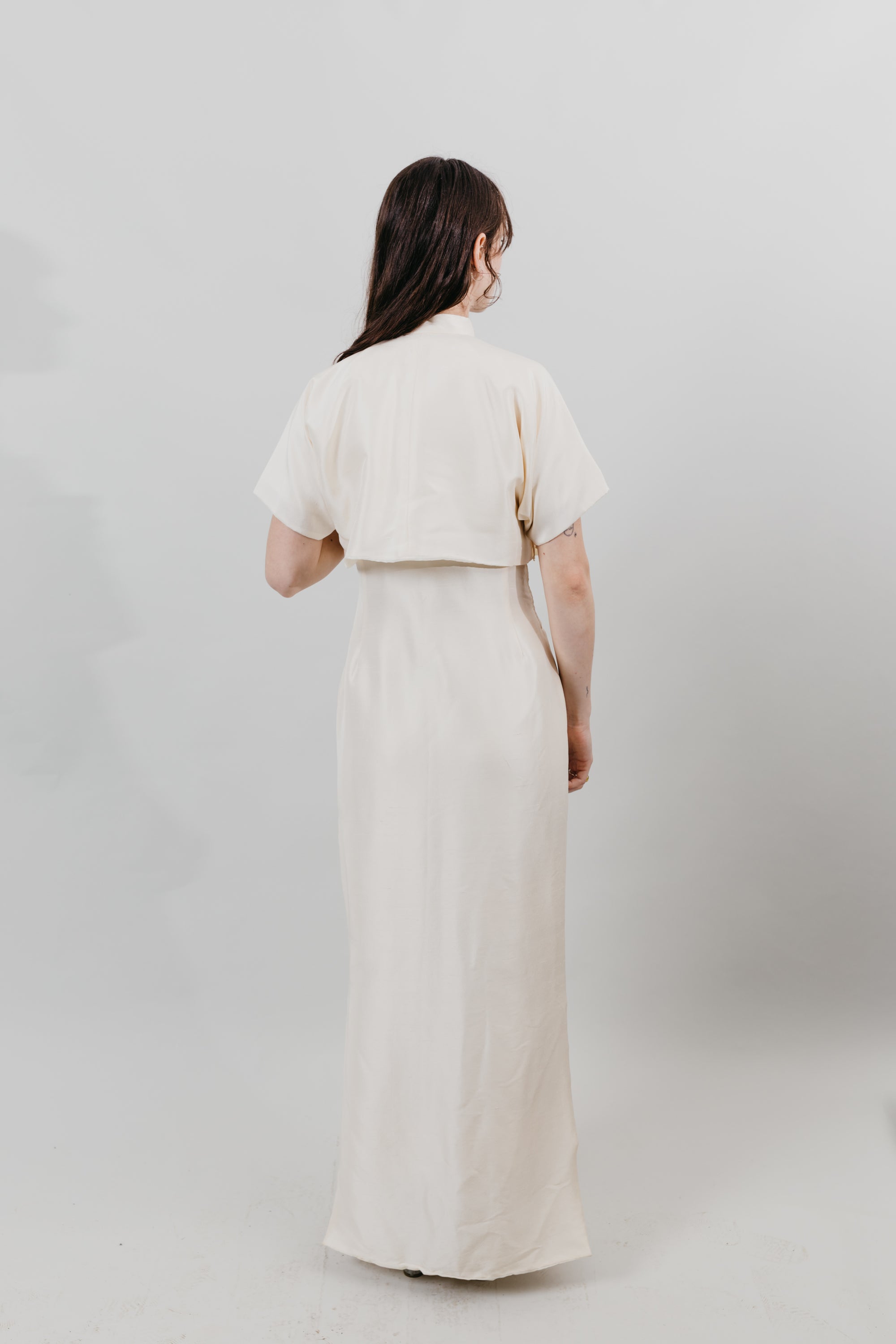 Woman wearing a white cheongsam - back view with white background.