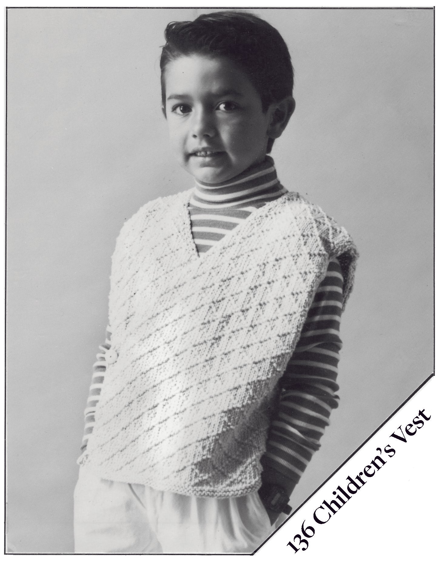 black and white photo of a boy wearing a knitted vest