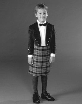 Black and white photo of boy wearing Kilt, Prince Charlie Jacket, and Argyle socks.