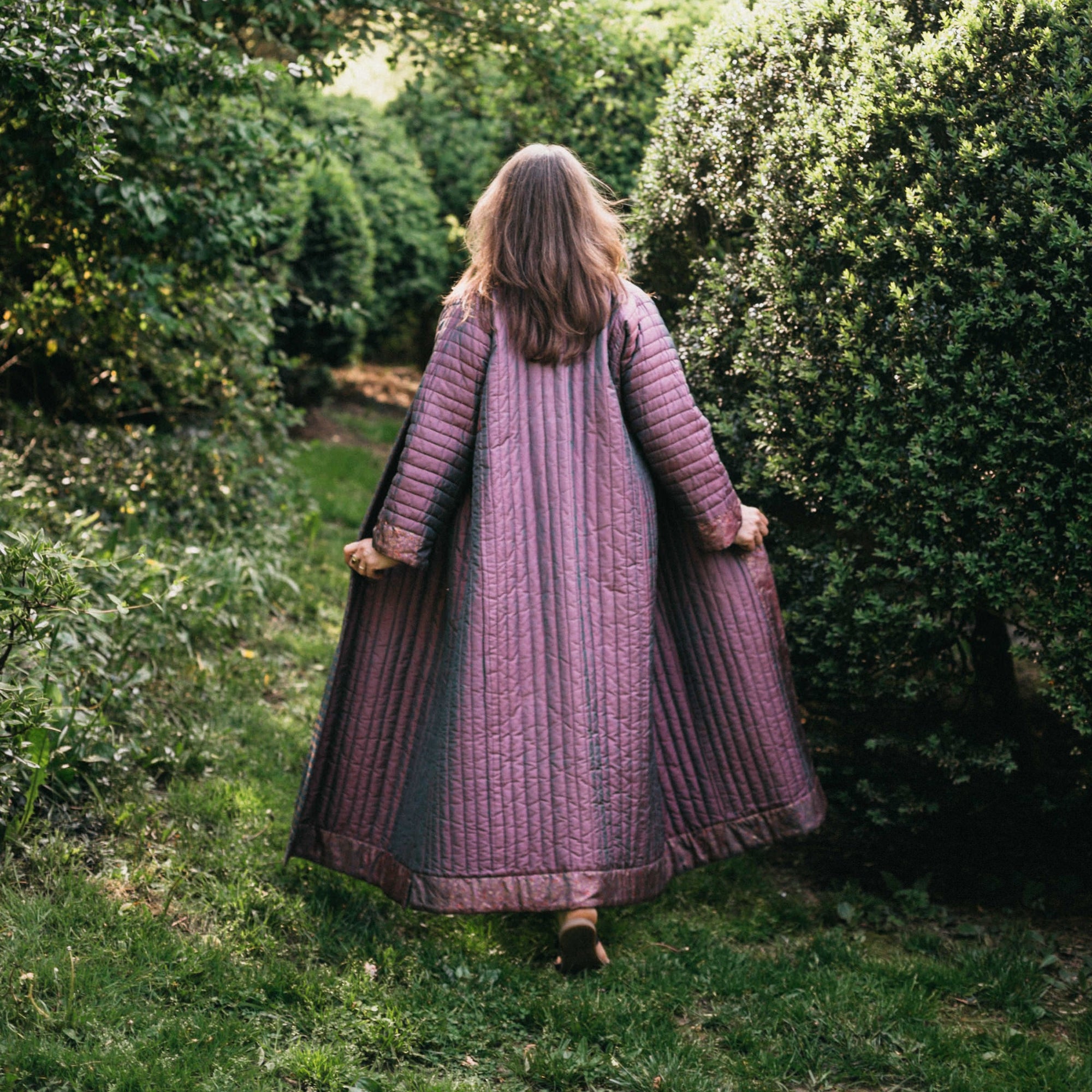 Woman walking away from camera wearing a quilted purple 106 Turkish Coat 