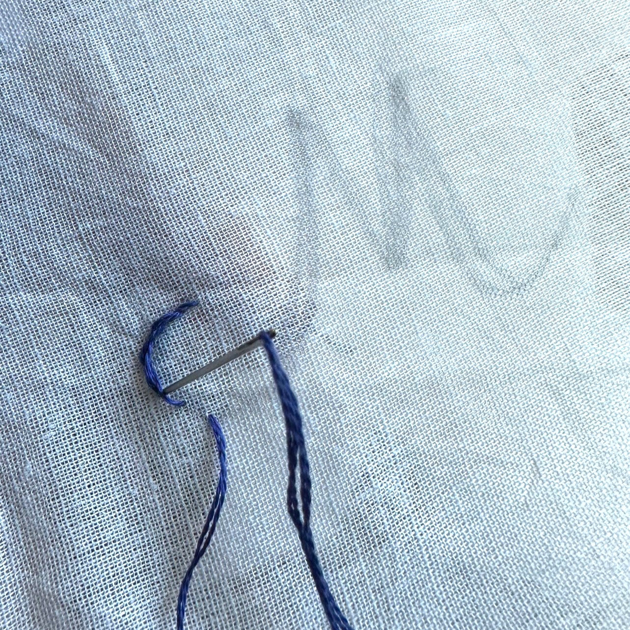 Starting a monogram on white fabric with blue thread.  letter M