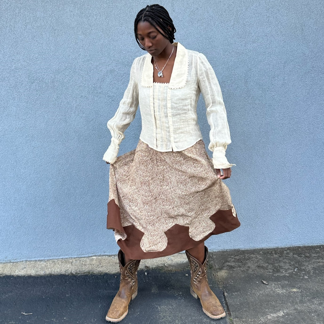African American Woman wearing a brown cowgirl skirt and cowboy boots and twirling