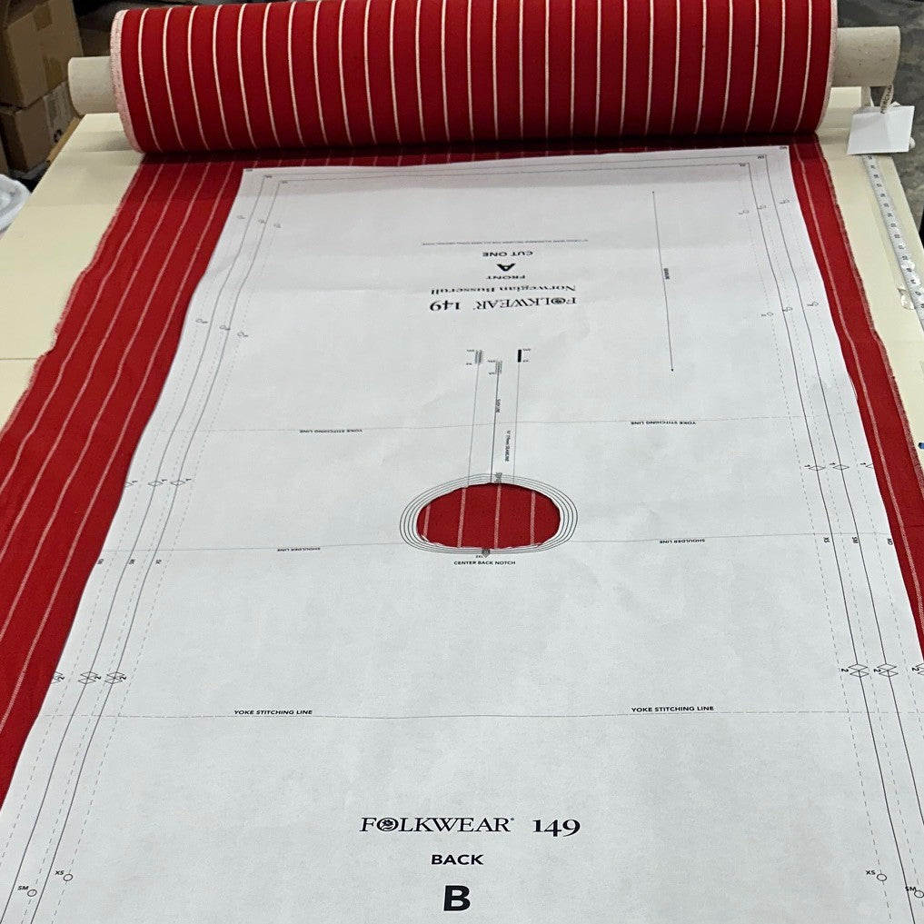 white pattern piece on a roll of red and white striped fabric on a table