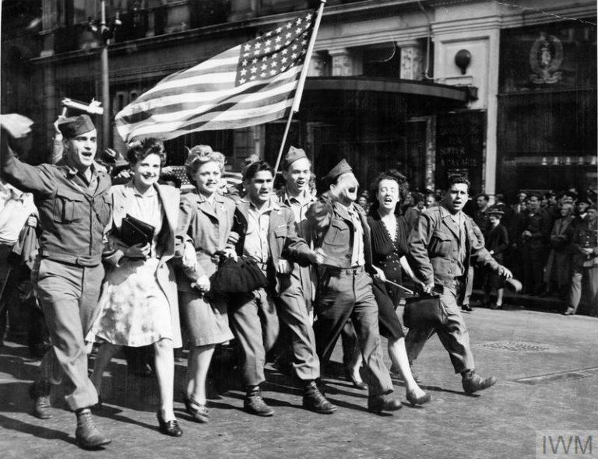 Photo of Wartime Men & Women marching in street with US Flag