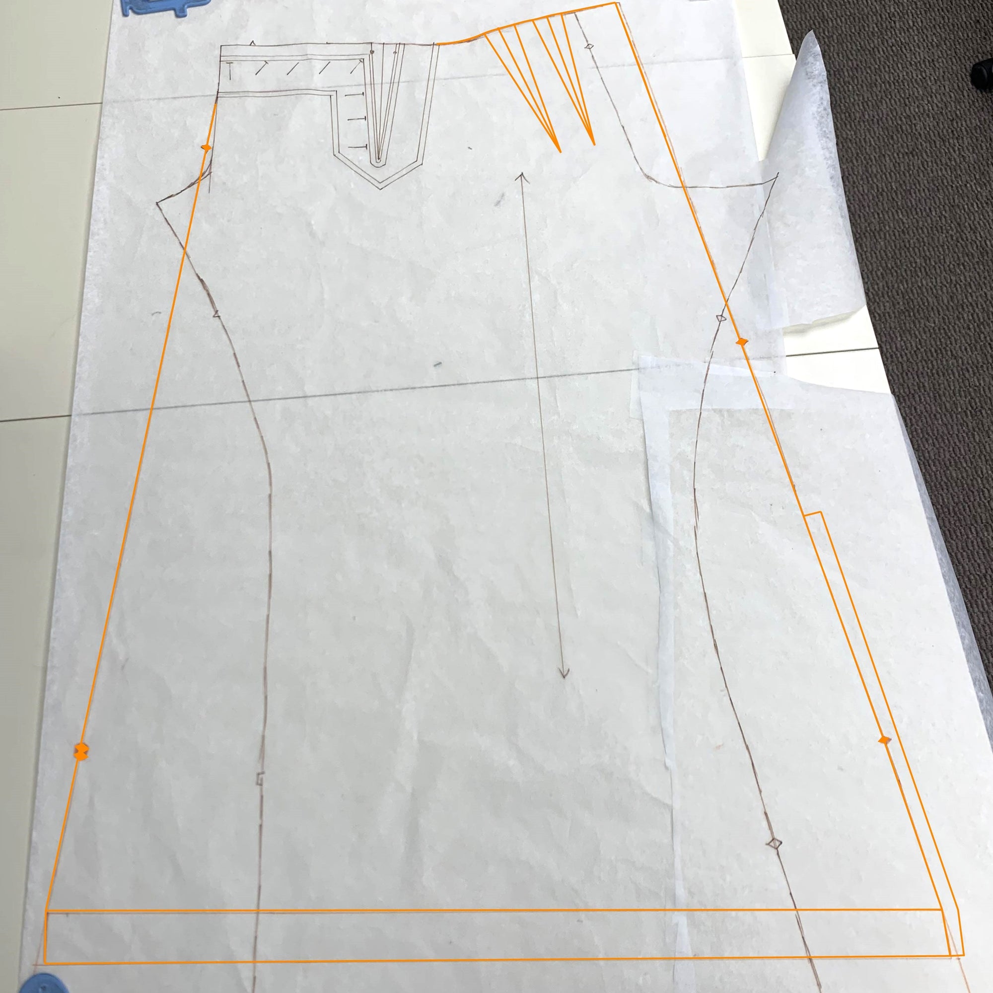 white tissue with a pattern penciled in and traced with an overlay of orange marker for the new skirt pattern.