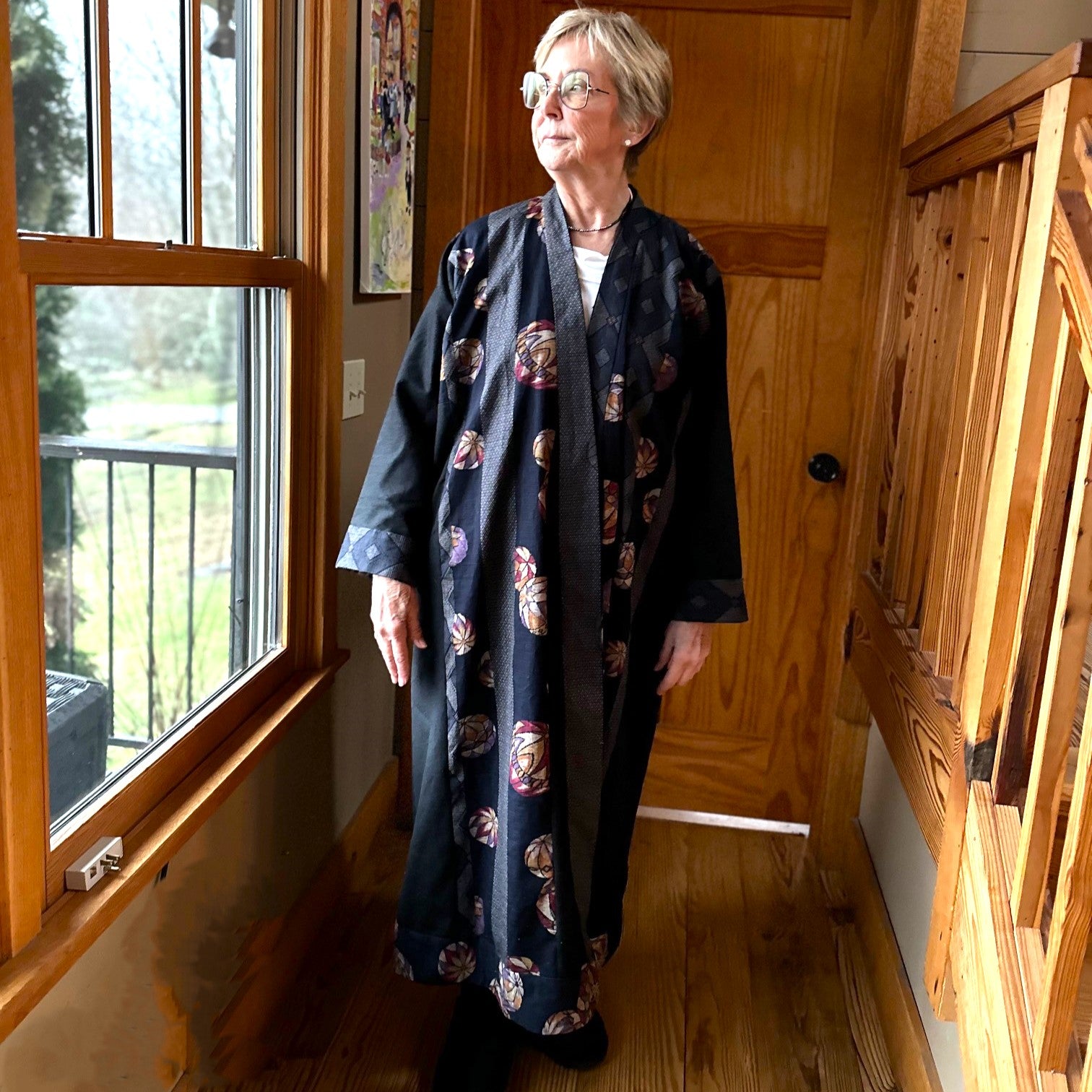 Woman standing by a window wearing a japanese print turkish coat