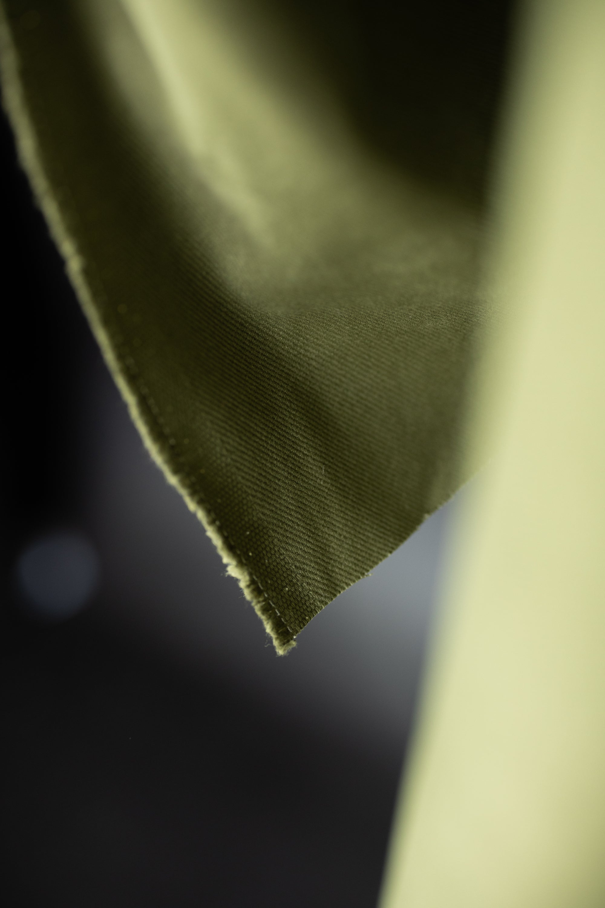 close up 12 oz sanded twill fabric in a spring green on a dark grey background.