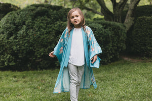 Child wearing a blue floral kimono standing in a garden