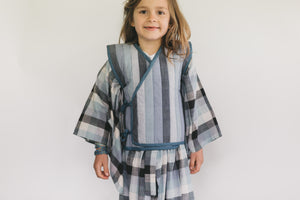 Child wearing a striped Kimono and vest against a white background