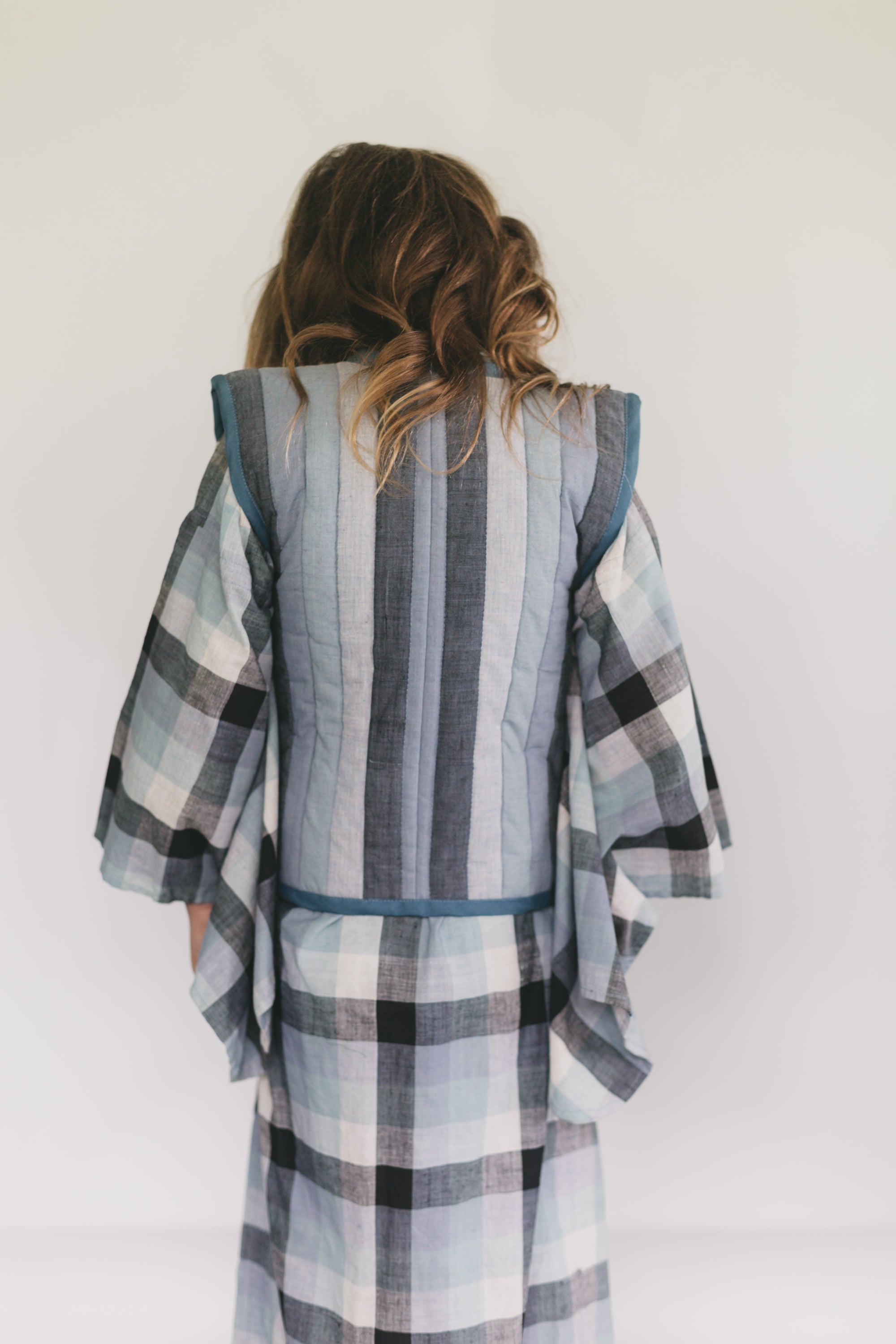 Girl wearing a plaid kimono-style garment against a white background