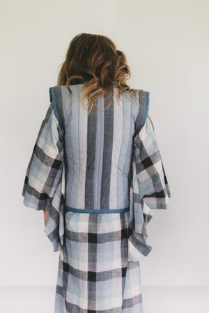Girl wearing a plaid kimono-style garment against a white background
