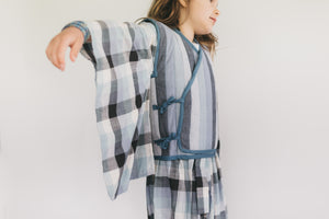 Girl wearing a plaid kimono-style garment against a plain background