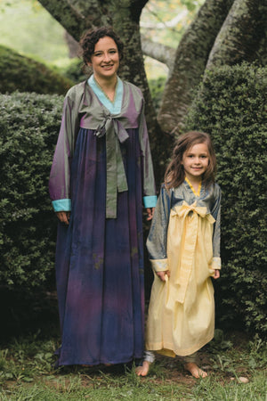 Photo of young woman and young girl standing side by side outdoors in the Han-Bok.  