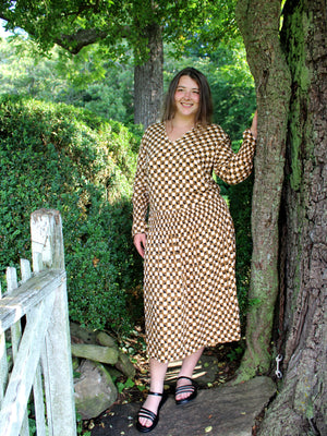 Woman by bushes wearing a long sleeved patterned tea frock