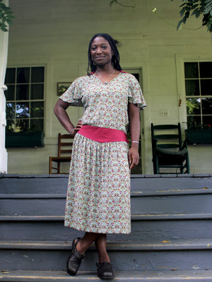 Woman standing on an outdoor staircase wearing a short sleeved vintage patterned tea frock