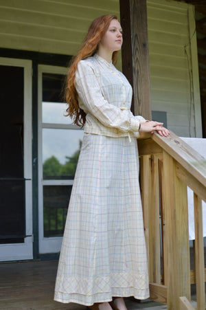 Young red head woman standing on a porch wearing 216 Schoolmistresses Shirtwaist and Skirt. 