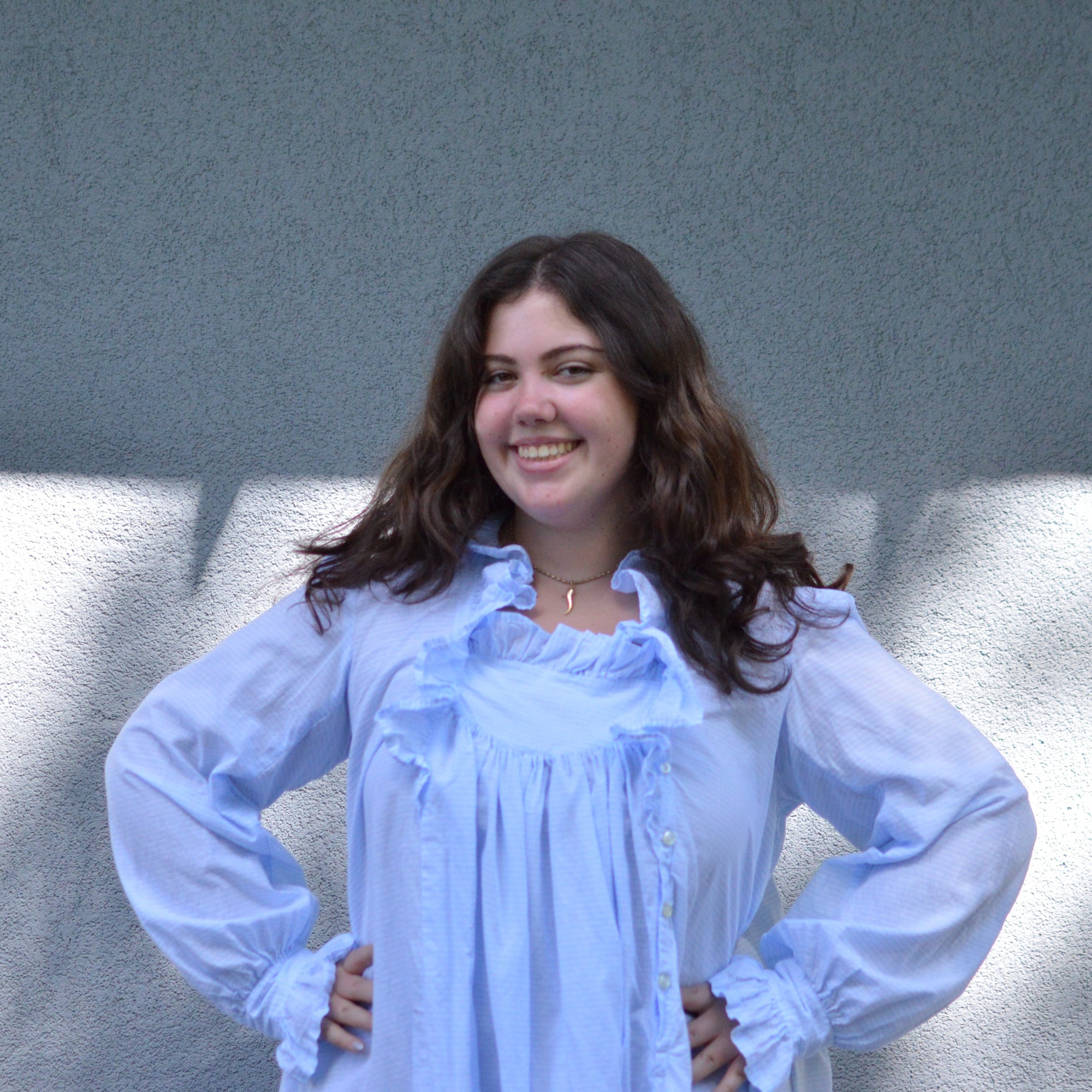 Closeup of top of blue night gown in front of grey wall.