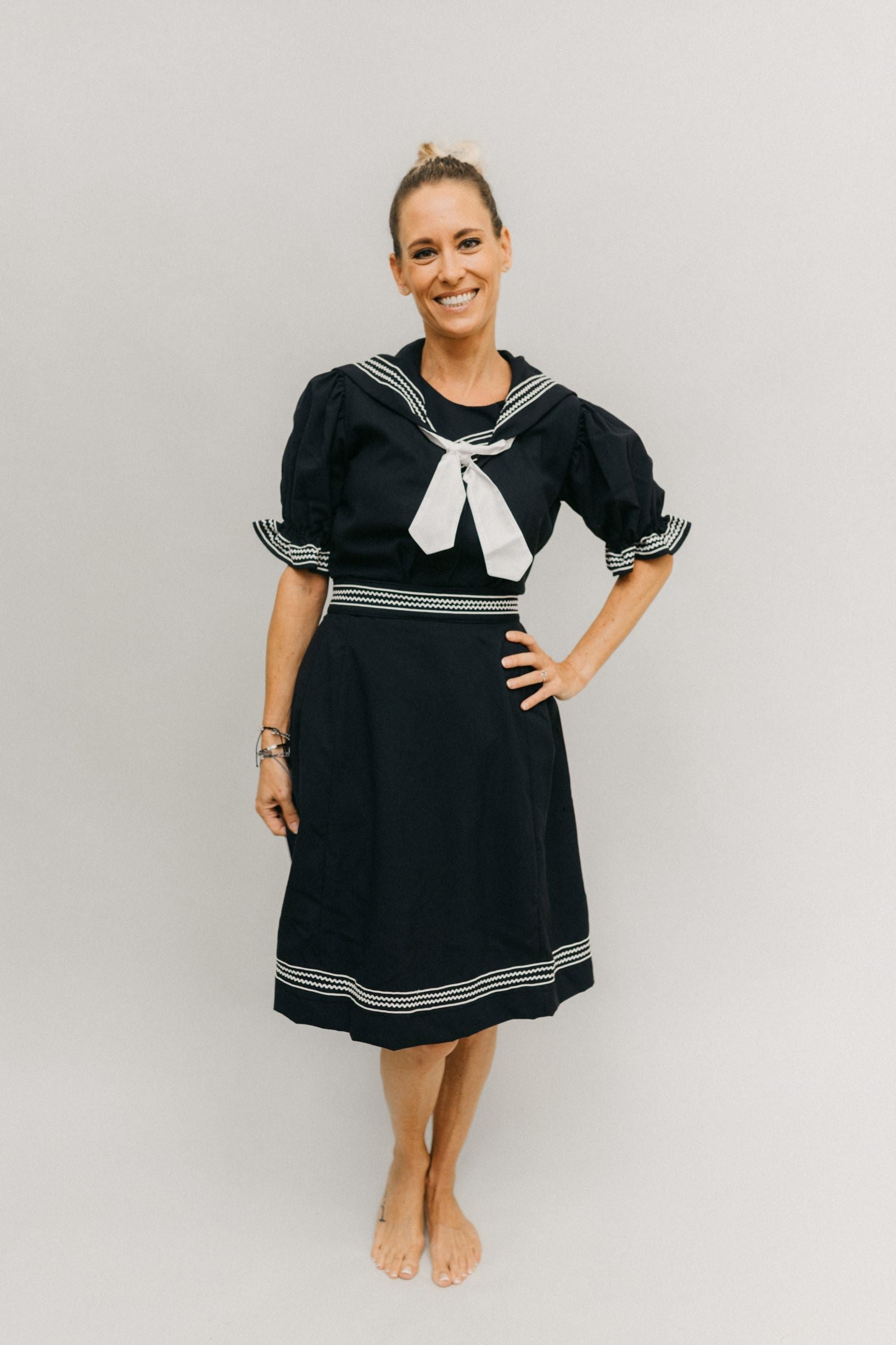 Blonde white woman smiling standing in front of a white studio backdrop with one hand on her hip wearing the 253 Vintage Bathing Costume.