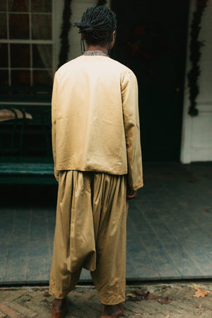 Person wearing a gold Algerian Suit standing in front of a door, with back to the camera.