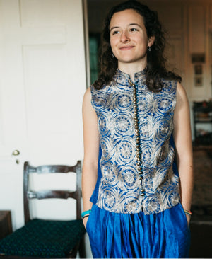 Woman wearing a blue and white patterned vest from the Algerian Suit indoors.