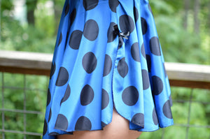 Close up of the skirt of a blue and black polka dot lingerie skirt with a black bow at the side hem.
