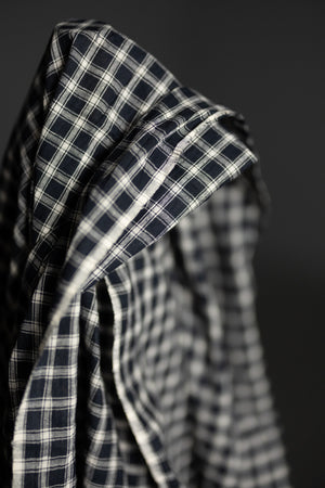 Close up of a roll of black and white check indian cotton on a dark grey background.