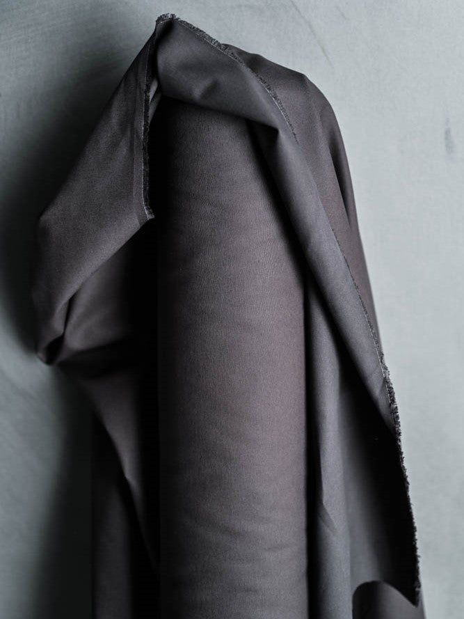 Top half of a bolt of dark grey fabric. 