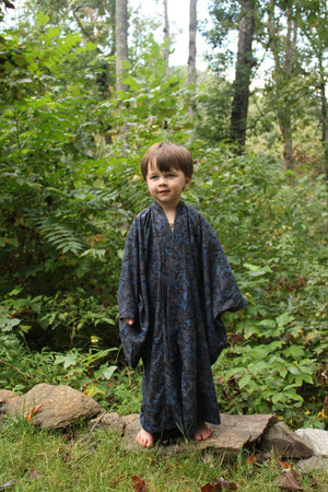 Boy wearing a dark blue kimono standing in a forest
