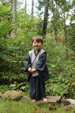 Child standing in a forest with greenery and trees in the background