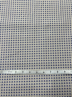 Fabric with a small cross pattern and a ruler for scale on a white background