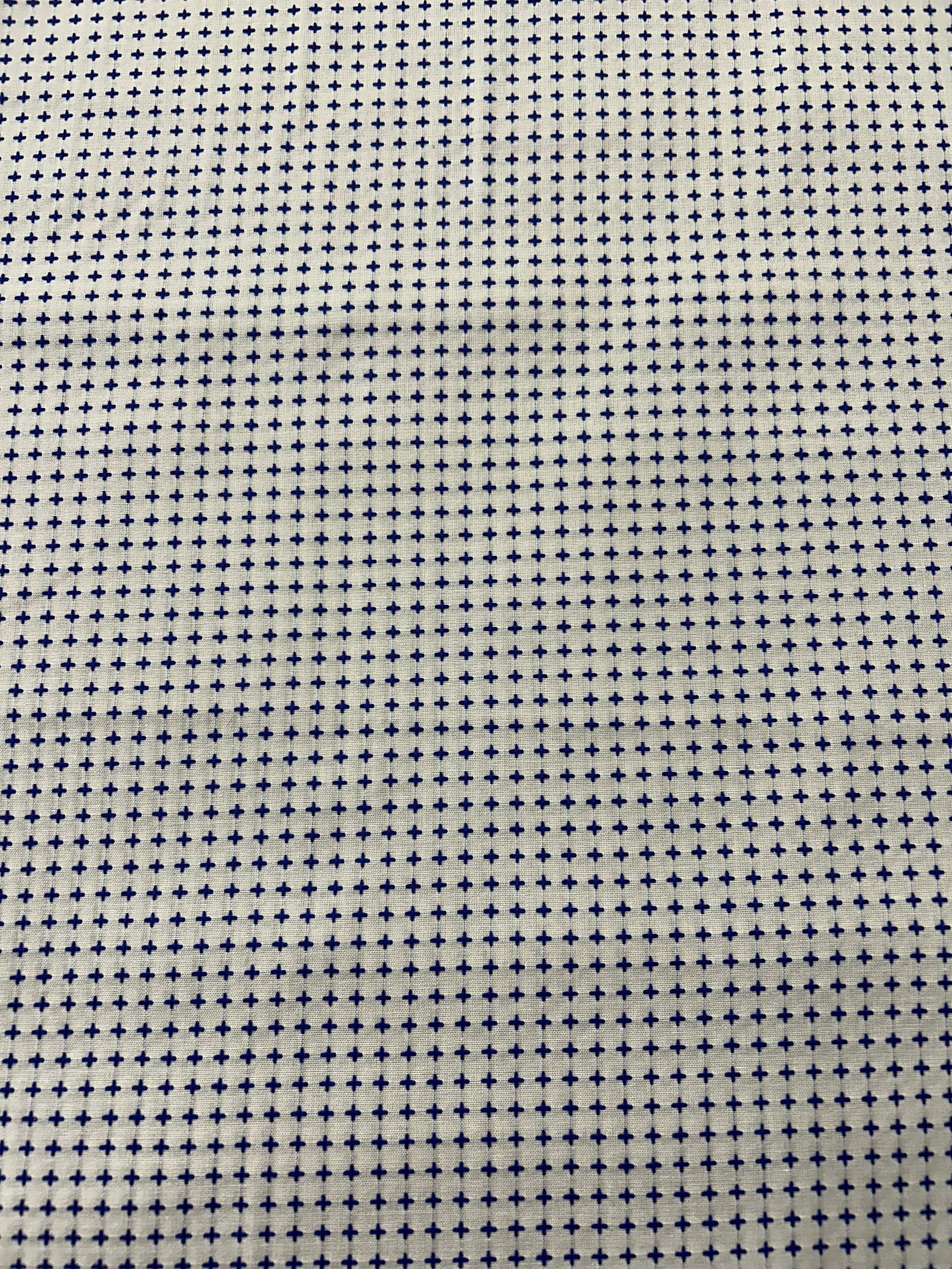 Fabric with a small cross pattern and a ruler for scale on a white background