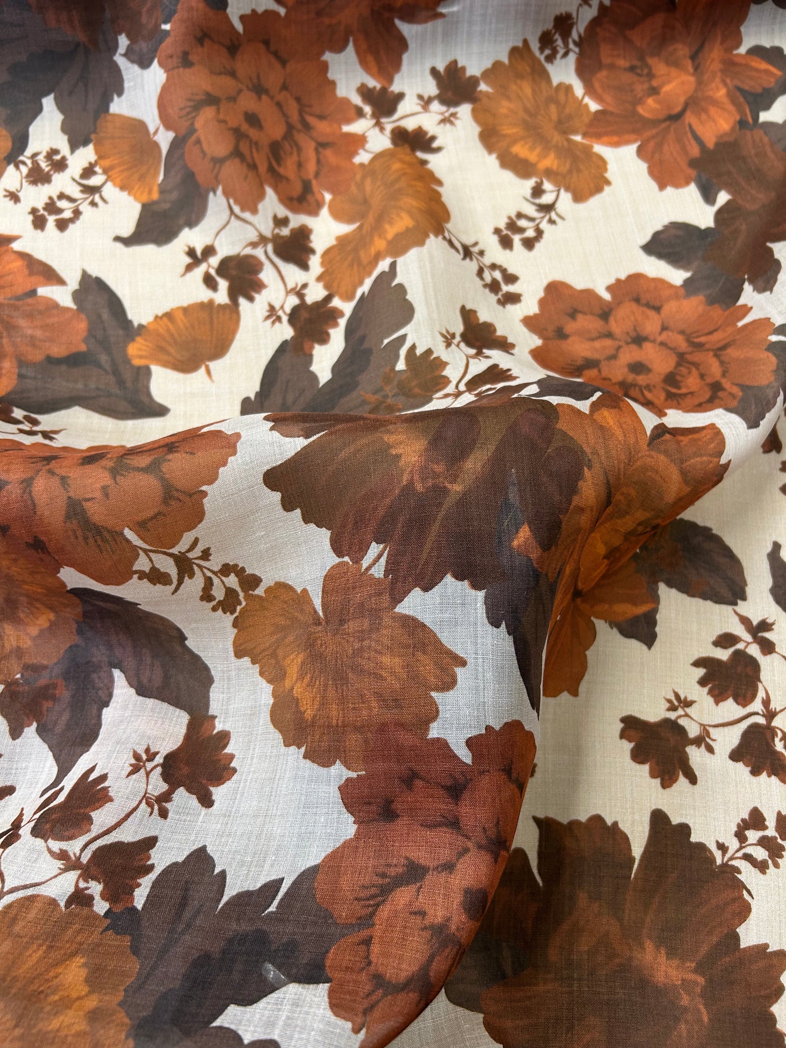 Floral peony pattern with brown and orange flowers on a light tan background.