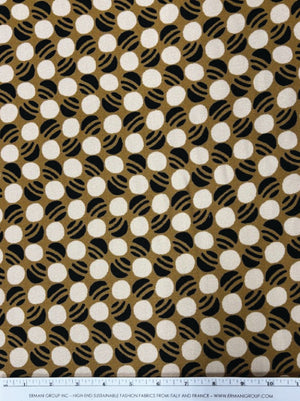 Fabric with a pattern of white circles on a brown background, with a ruler at the bottom for scale.