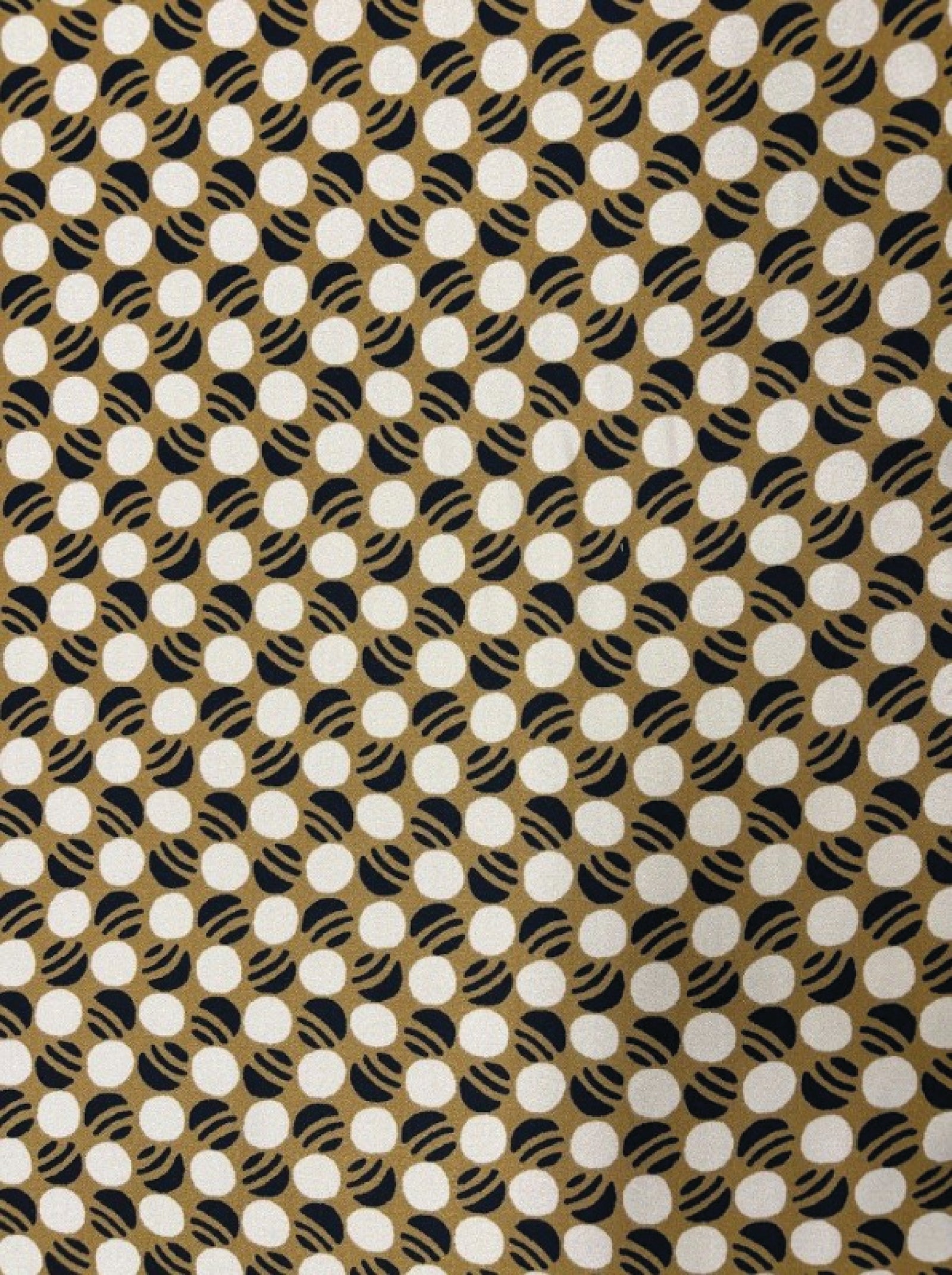 Fabric with a pattern of white circles on a brown background, with a ruler at the bottom for scale.