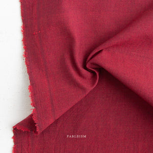 Close-up of red fabric with 'Fableism' branding on a white background