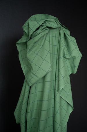 cotton linen fabric in a meadow green with grey blue checks, on a dark grey background.