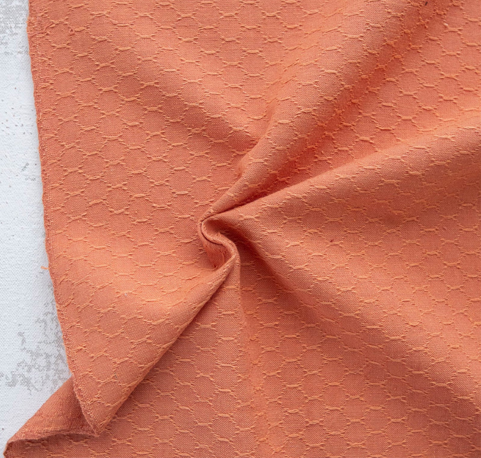 Close-up of textured peach fabric on a light gray background