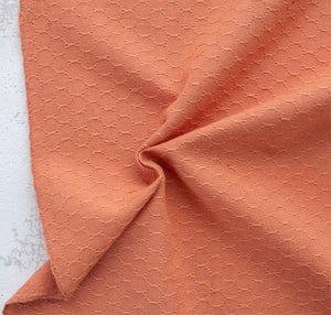 Close-up of textured peach fabric on a light gray background