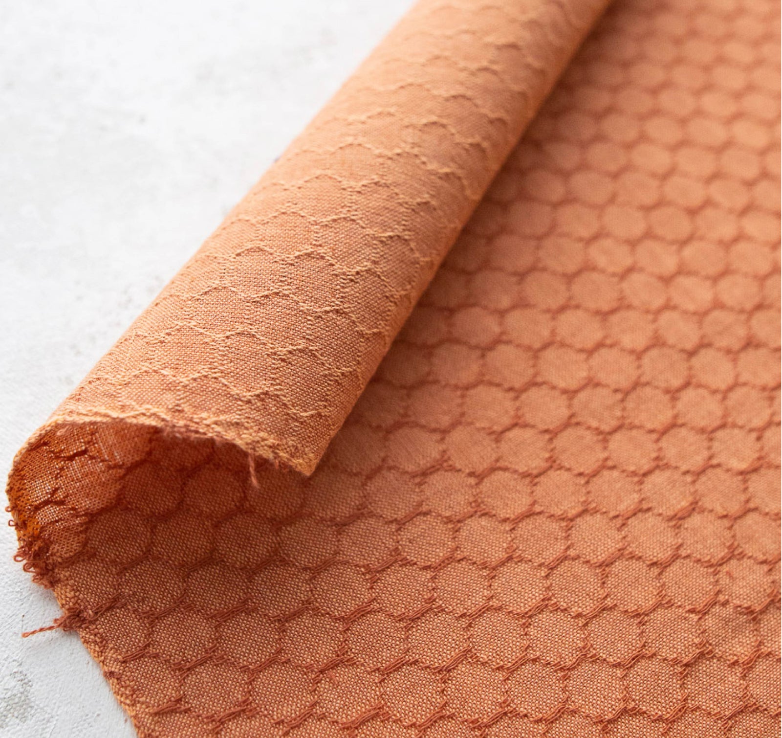 Close-up of textured peach fabric on a light gray background