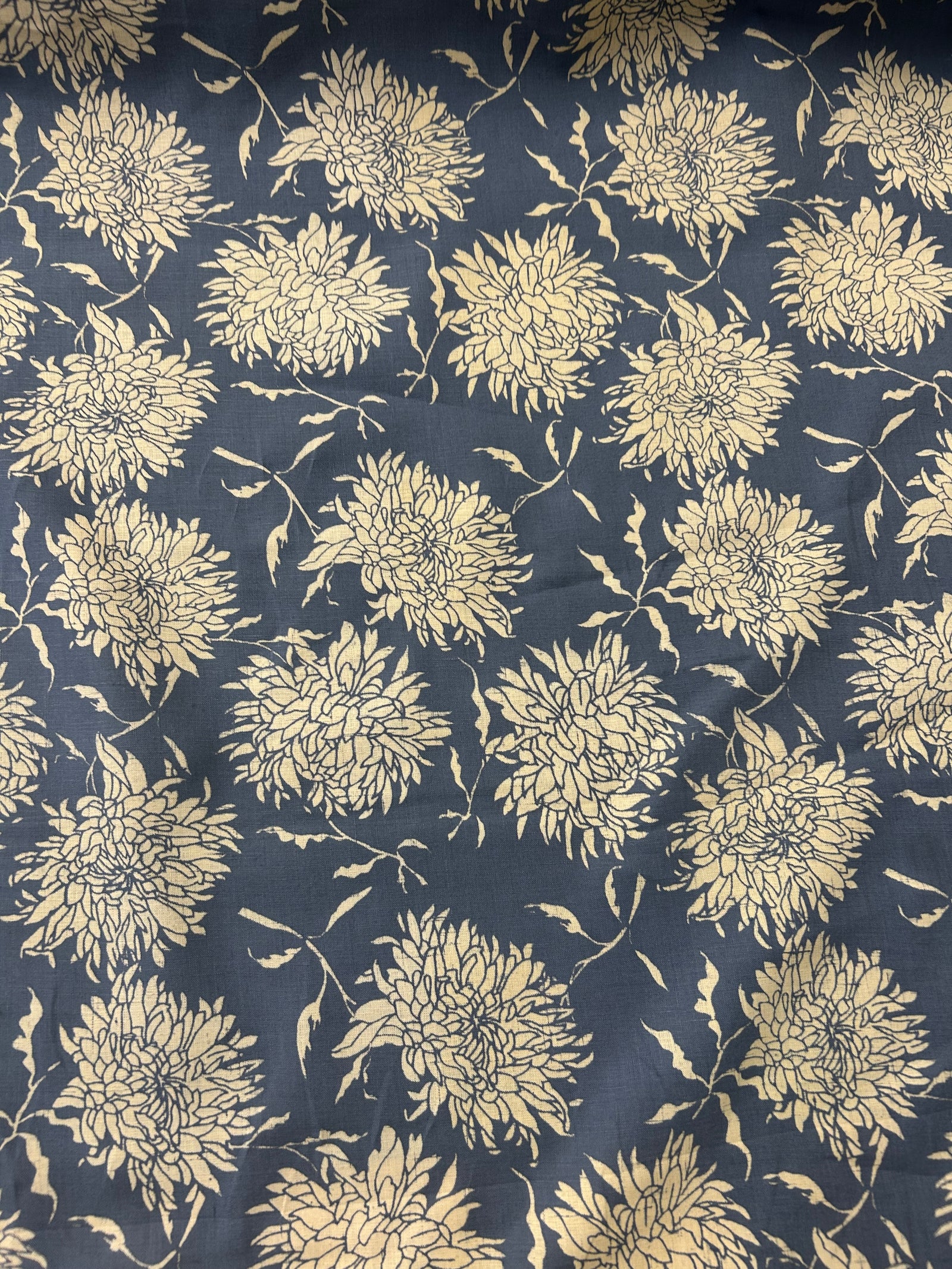  floral print fabric with off white peonies on a dark blue background, with a measuring tape on top.