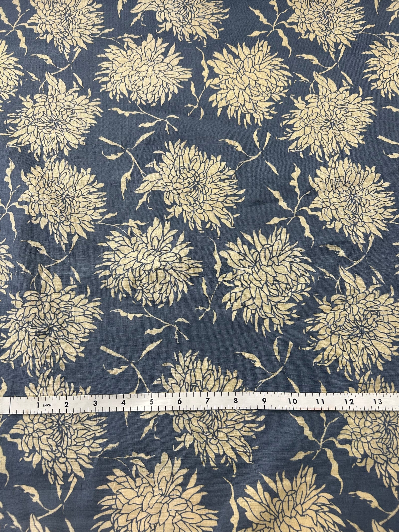  floral print fabric with off white peonies on a dark blue background, with a measuring tape on top.