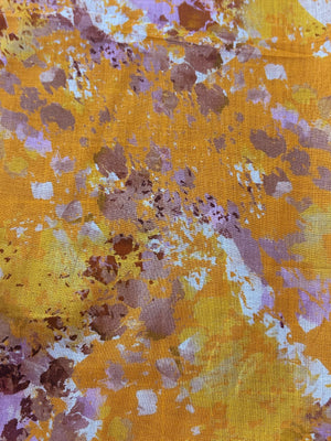 Yellow fabric with watercolor splashes in brown, purple, and white.
