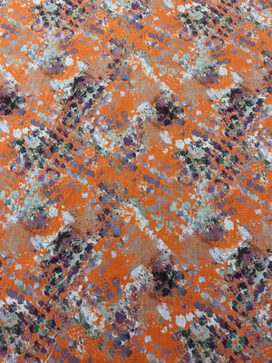 Orange fabric with watercolor splashes in brown, purple, and white.